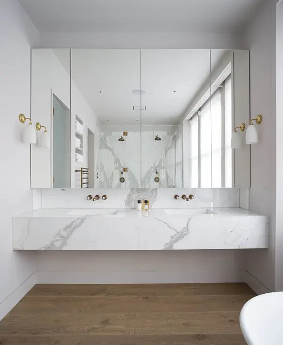Floating marble bathroom vanity with double sinks, wall-mounted faucets, and large mirrored cabinets
