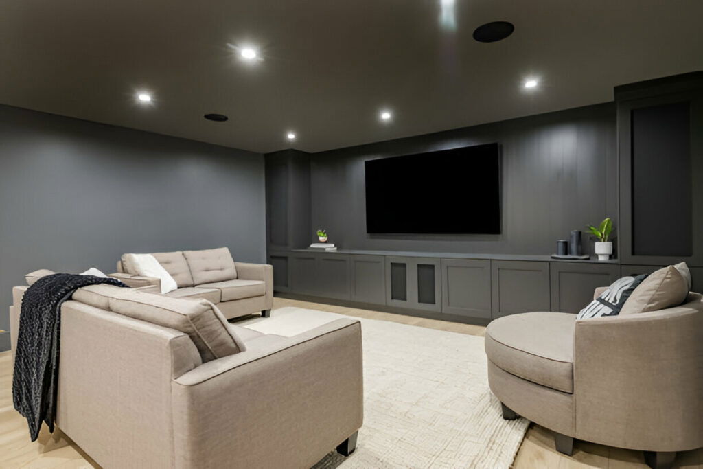 20 Inspiring Small Garage Conversion Ideas 25 Modern home theater room with gray walls, built-in cabinets, a large flat-screen TV, and comfortable beige seating