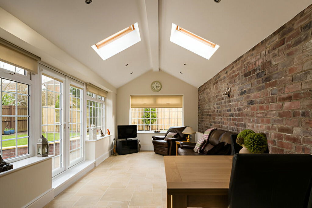 20 Inspiring Small Garage Conversion Ideas 15 Bright sunroom with large windows, skylights, exposed brick wall, and cozy seating area