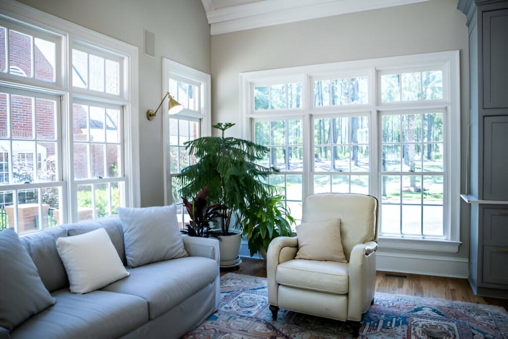 Bright living room interior featuring comfortable seating, houseplants, large windows, and ample natural light