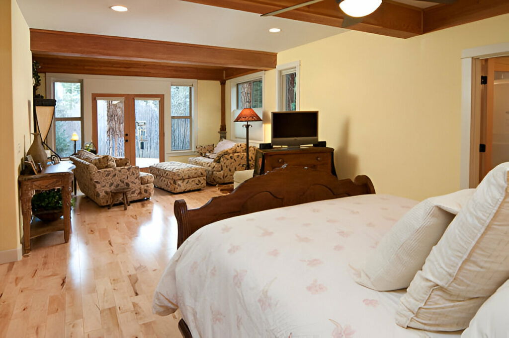 Warm and inviting bedroom with a cozy seating area, wooden accents, and access to an outdoor patio