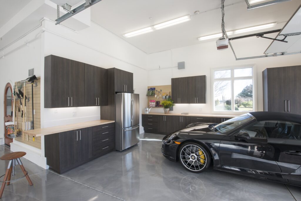 20 Inspiring Small Garage Conversion Ideas 21 High-end residential garage featuring custom dark wood cabinetry, a sleek polished concrete floor, stainless steel appliances, and a luxury sports car.