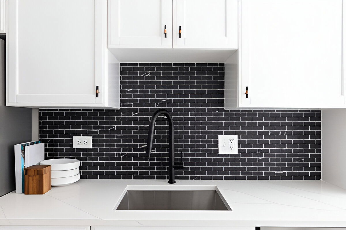 Modern kitchen with white shaker cabinets, black subway tile backsplash, and a matte black faucet over a stainless steel sink.