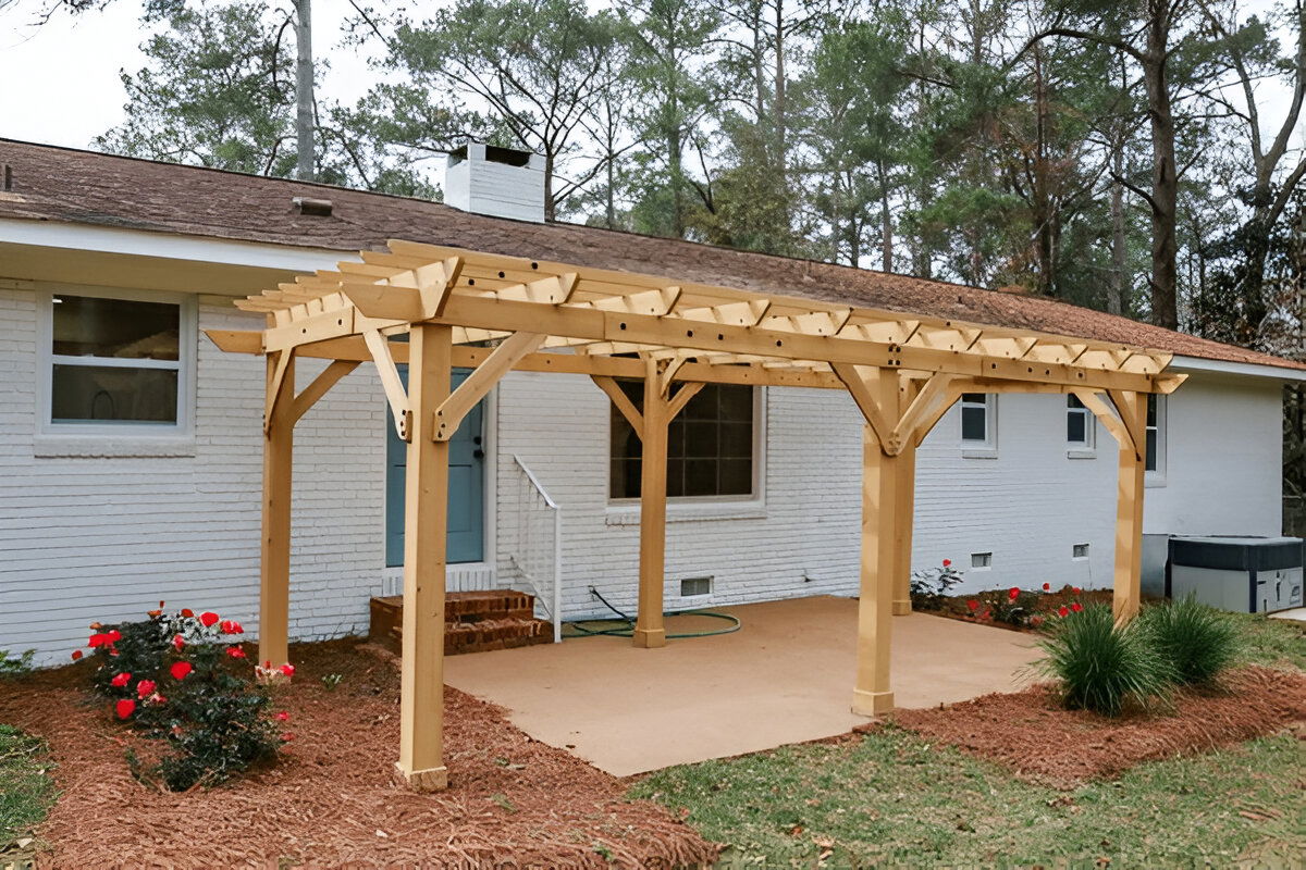 Backyard wooden pergola attached to a white brick house