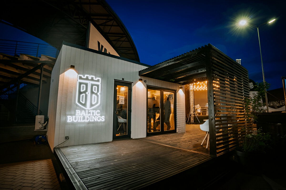 Modern modular building with wooden slatted pergola and illuminated signage at night
