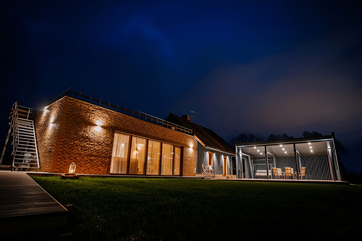 Modern brick home with illuminated patio and covered pergola at night