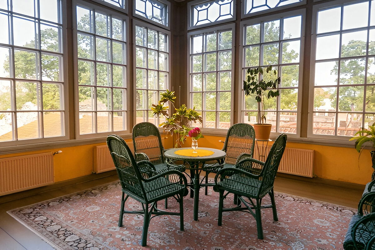 Vintage sunroom with wicker furniture and panoramic garden windows