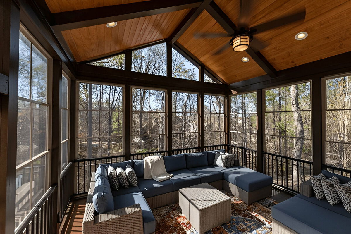 Sunroom with wood-paneled vaulted ceiling, large windows, and a blue sectional sofa
