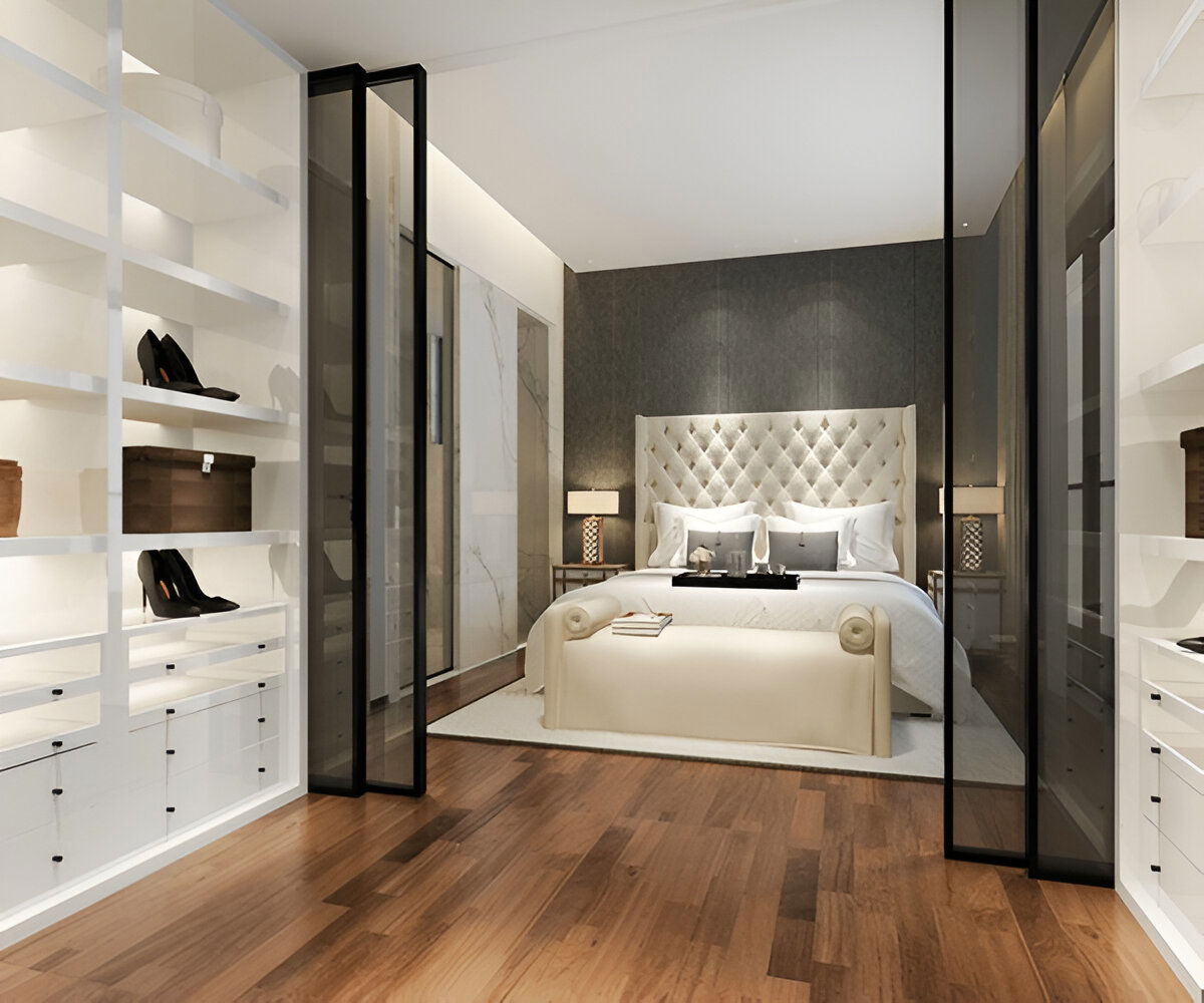 Modern walk-in closet with glass doors and a view into a luxury bedroom 