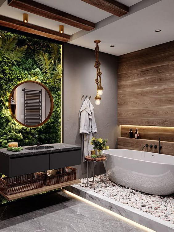 Modern nature-inspired bathroom with green plant wall, freestanding bathtub, wooden accents, and pebble flooring.