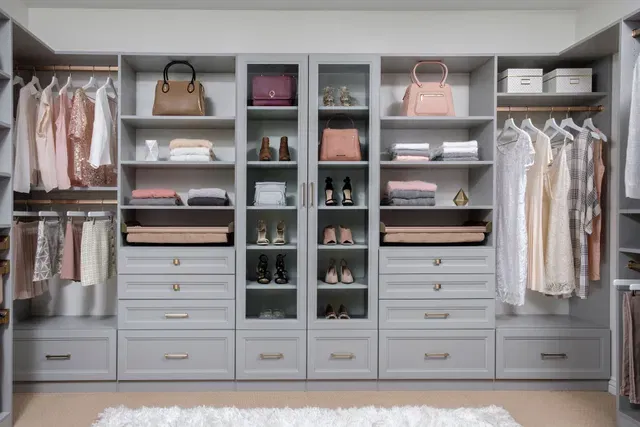 A spacious and meticulously designed walk-in closet featuring built-in shelves, hanging rods, drawers, and storage compartments in a neutral color palette