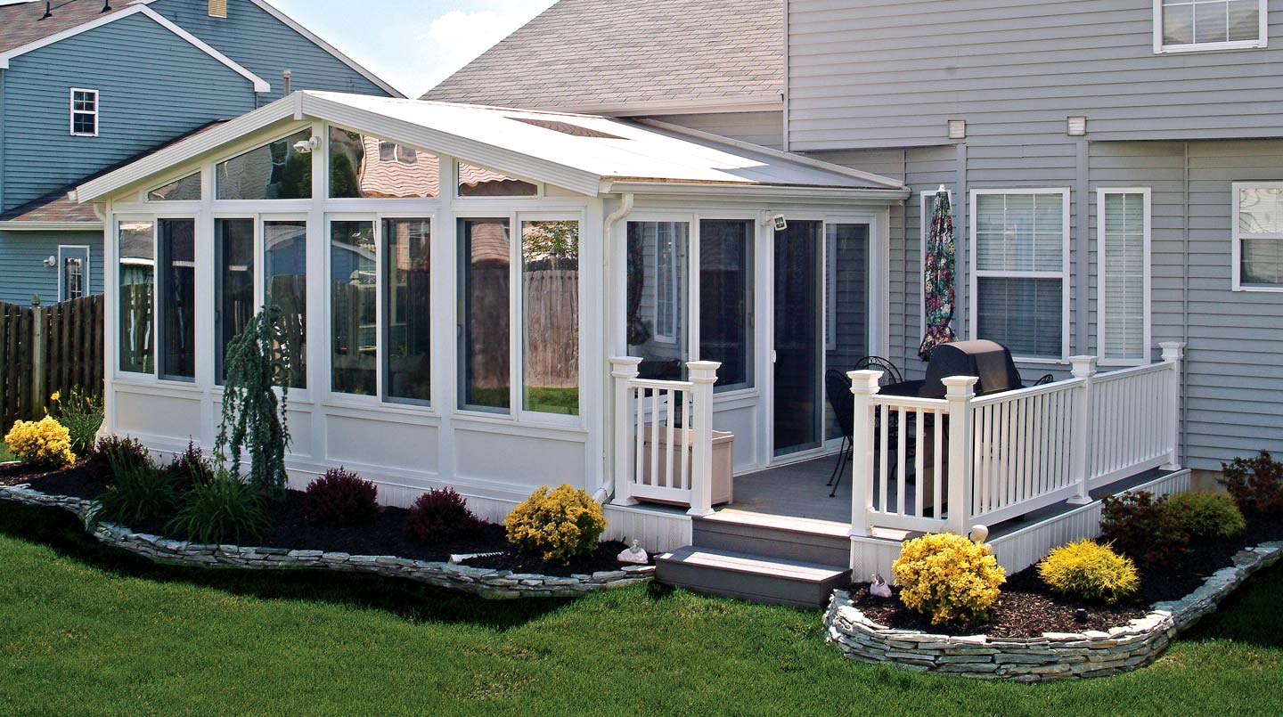 White-framed sunroom extension with sliding glass doors and a cozy patio area
