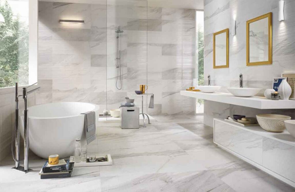 Bright modern bathroom featuring a freestanding oval tub, dual vessel sinks, walk-in shower, and large marble-look tiles