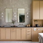 Bathroom featuring light wood cabinetry, black countertops, dual rectangular mirrors, and soft tile backsplash