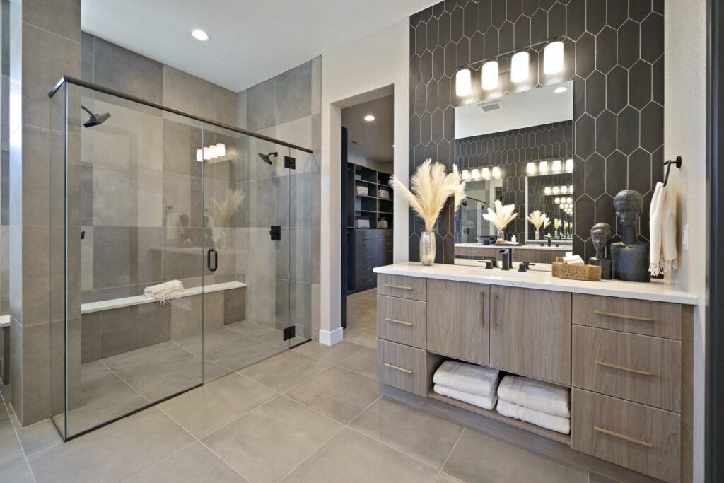 Modern bathroom featuring a spacious glass-enclosed walk-in shower, floating vanity with wood finish, and geometric black tile accent wall.