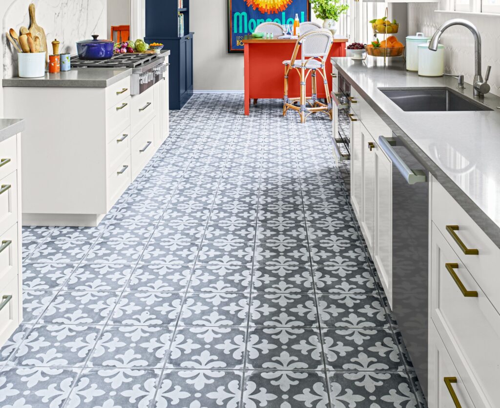 Kitchen with gray and white patterned cement tiles, white cabinets, and a red island.