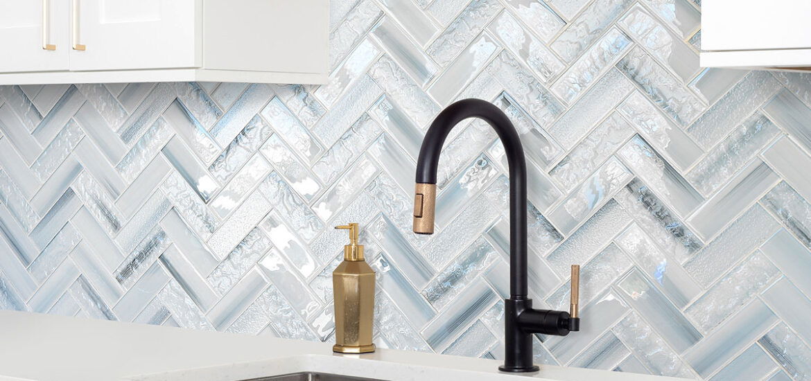 Contemporary white kitchen with blue glass herringbone backsplash, black matte faucet, and quartz countertop