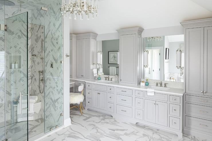 Luxurious master bathroom with gray cabinetry, marble tile floors, built-in vanity space, and a frameless glass shower enclosure.