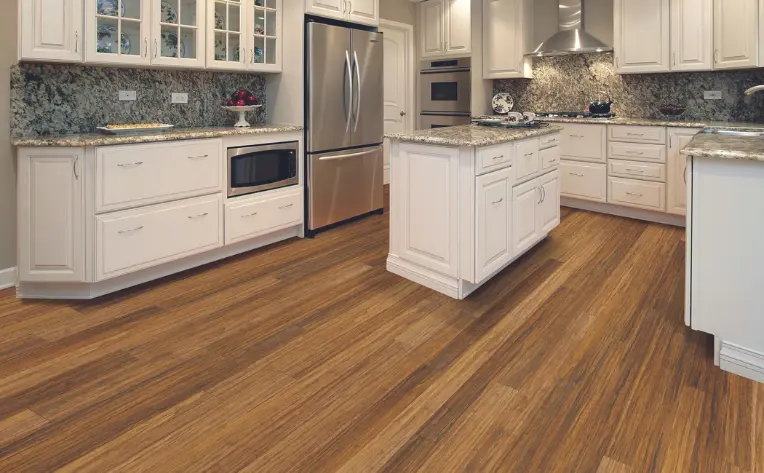 Sustainable bamboo flooring in a modern kitchen with white cabinetry, granite countertops, and stainless steel appliances.