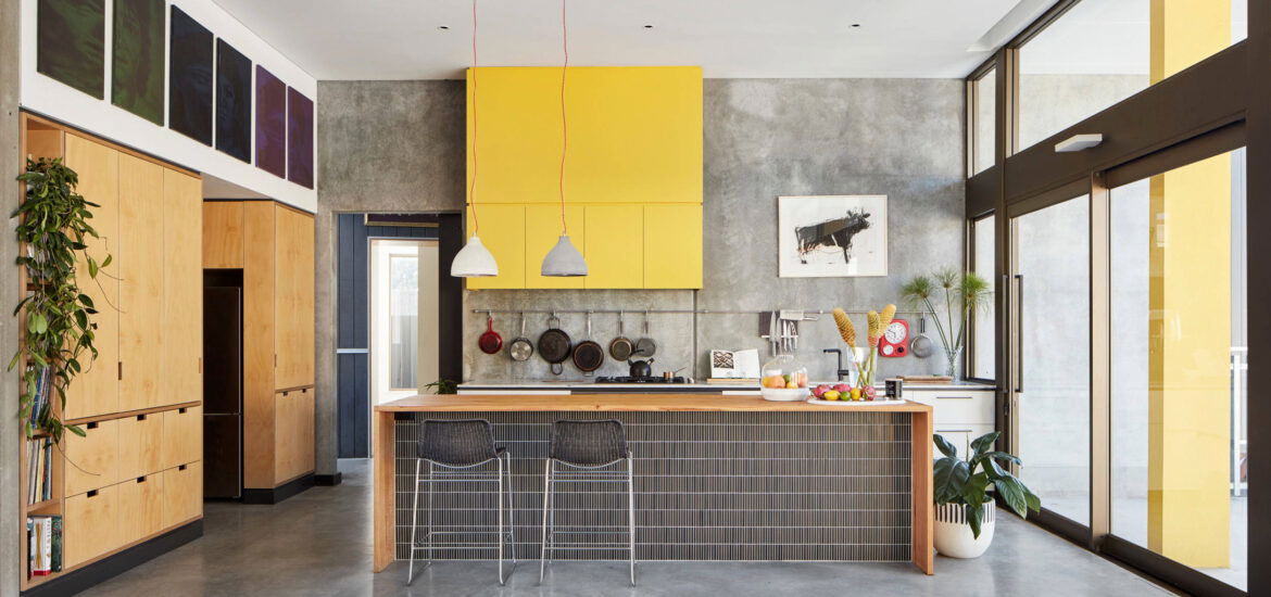 Contemporary kitchen with concrete floors, yellow upper cabinets, wood accents, and large glass doors