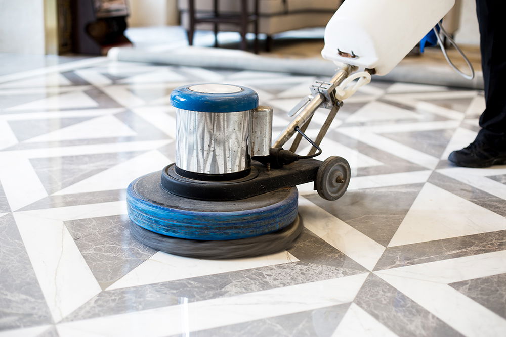 Close-up of a floor buffer polishing a marble tile floor with a geometric patte