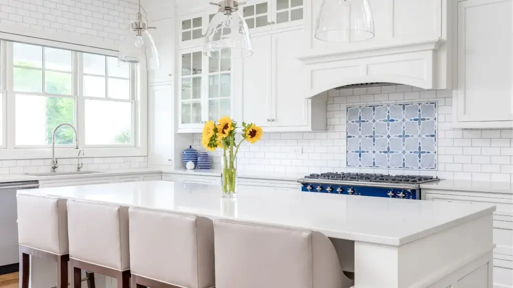 Modern white kitchen with a blue patterned tile backsplash and sunflowers on a large island