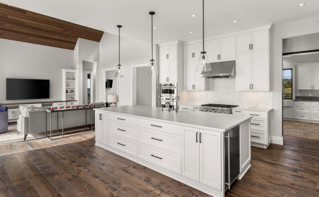 Modern open-concept kitchen featuring white shaker cabinets, stainless steel appliances, a large island, and dark hardwood flooring