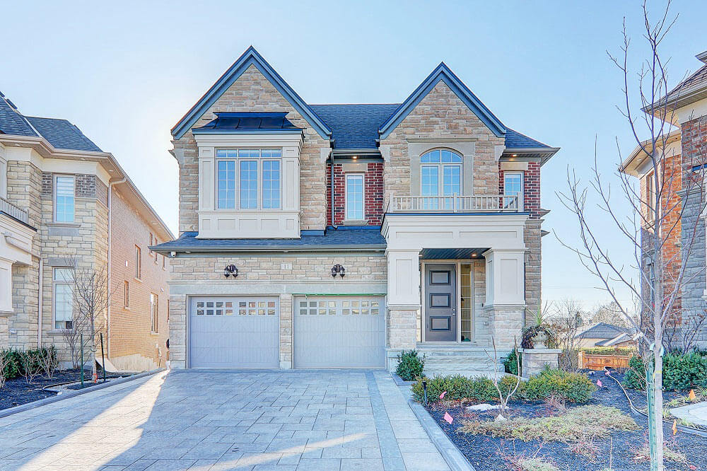 Elegant two-story custom home with stone façade, large windows, and double garage.