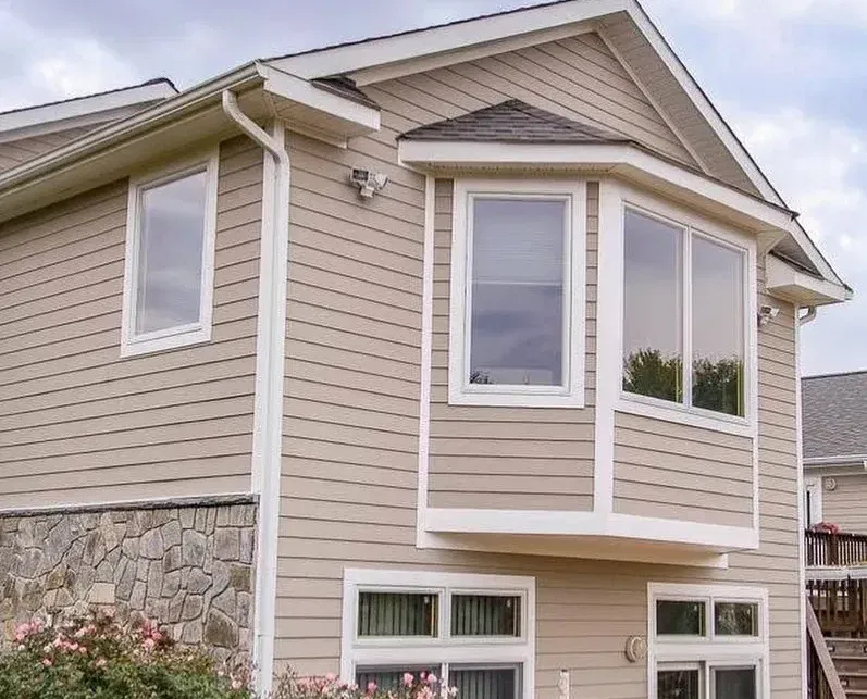 Cantilevered bump out addition on a beige house with white trim.
